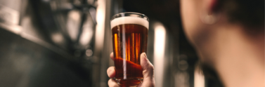 man holding up glass of beer