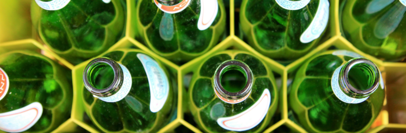 the top of empty glass bottles in a yellow container
